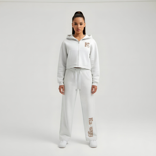 Person wearing a white tracksuit with brand logo on a light gray background